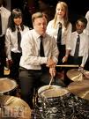 Man (Ed Balls) playing drum with school pupils looking