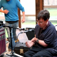 A musician playing live at a venue, singing into a microphone