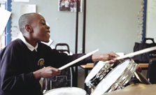Young pupil smiling playing drum kit