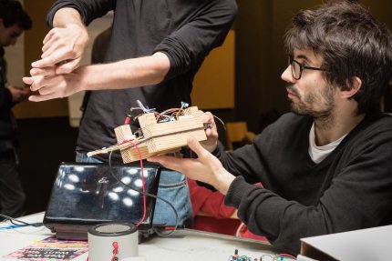 A young male holds up a piece of basic technology he is developing
