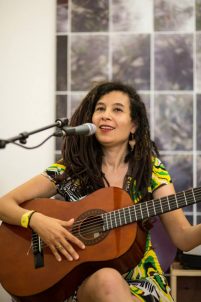 Musician Cina pictured performing with guitar and microphone