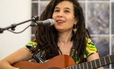 Musician Cina pictured performing with guitar and microphone