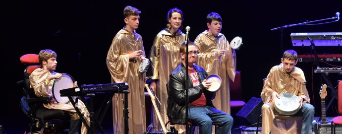 6 band members onstage in long gold robes playing different instruments