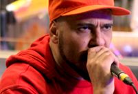 Brazilian rapper Billy Saga performing wearing a red baseball cap and red hoodie