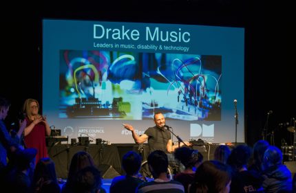 Daryl hosting the event in front of a large screen of projections