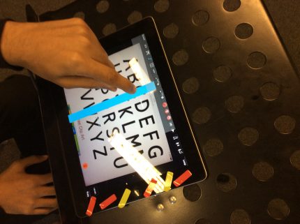 ipad with alphabet displayed and a person pressing the screen