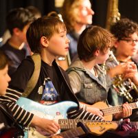Young children in casual dress play instruments together