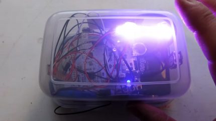 A tupperware box full of wires shines with a bright light in one corner