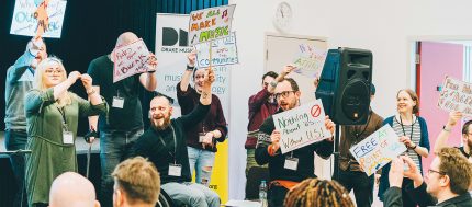 The Drake Music team are staging a protest with colourful signs onstage at a conference