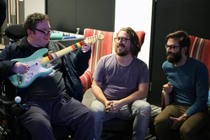 Sam, Billy and Andy at DMLab. Sam is holding a reimagined version of a Guitar Hero guitar which now is an actual instrument