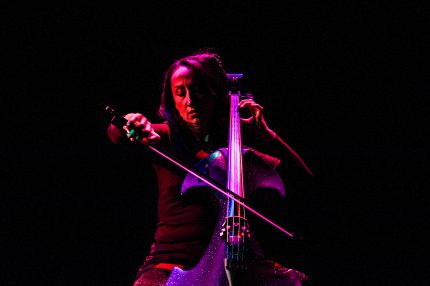 Joanne is onstage with a sparkly cello, bathed in red light