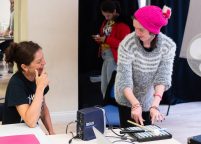 Two women smile as they trigger sounds with music technology