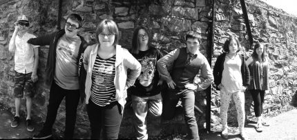 Young people lean against a wall. They are nonchalant, cool, goofy, silly, defiant and more.