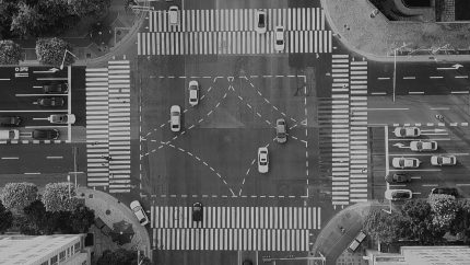 A view of a city crossing from overhead, grids and people and cars