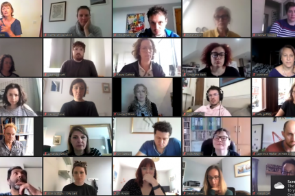 A screen capture from a Zoom call shows lots of faces in a grid format
