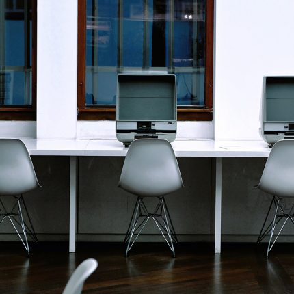 Chairs and desks in what looks like a school computer room. The spaces for the computer are empty.