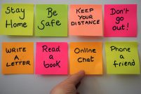 Neon post it notes saying Be Safe, Keep your Distance, Online Chat, with a hand reaching out to one.