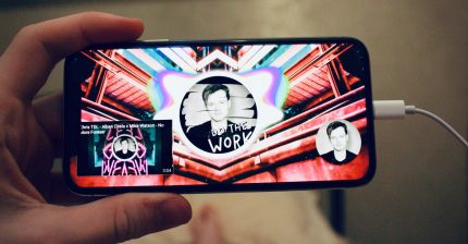 A hand holding a phone playing youtube videos with the words Do The Work visible onscreen