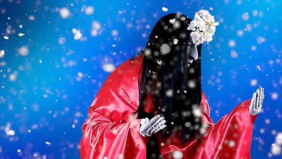 A figure with long black hair and a red robe against a blue background, very high contrast. There is snow coming down in front.