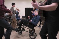 Young musicians learning folk music and dances, the focus of the picture is a young man in a wheelchair, dancing.