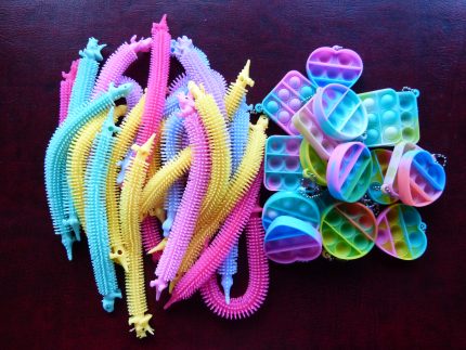 Heart and snake shaped purple, yellow, pink and blue silicon fidget toys in a pile on a table.