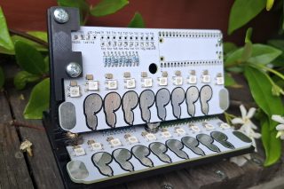 A piece of hardware that is used to control MIDI messaging. It has silver touchpads in the shape of finger prints and LED lights that are used to indicate when a sensor has been touched.