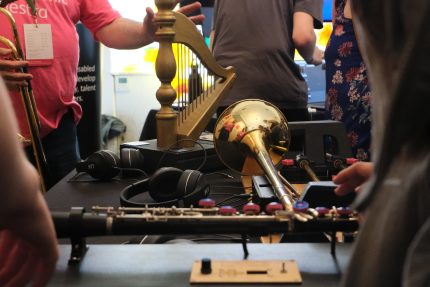Two touch-based adapted instruments, the Touch Harp and Touch Trombone, placed next to each other on a black table cloth.