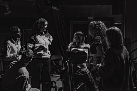 A black and white group picture of 5 people, our Emergent Artists, plus a support technician. The group are in conversation, the picture is very natural.