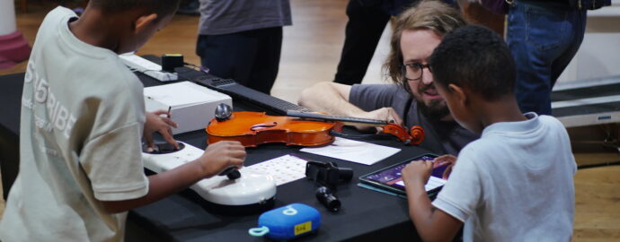 Two young children playing with several accessible instruments laid out on a table.