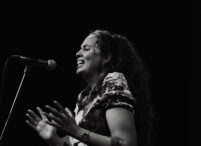 A black and white image of a Disabled musician performing on stage.