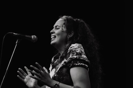 A black and white image of a Disabled musician performing on stage.