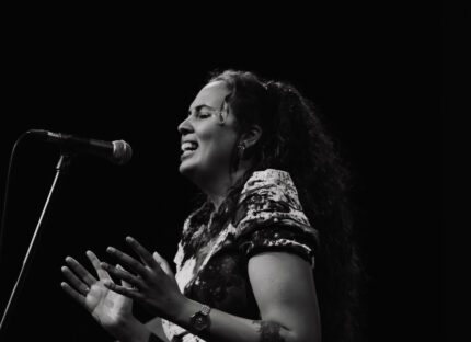 A black and white image of a Disabled musician performing on stage.
